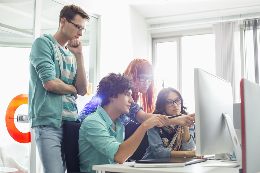 A team of young professionals collaborating on a computer.