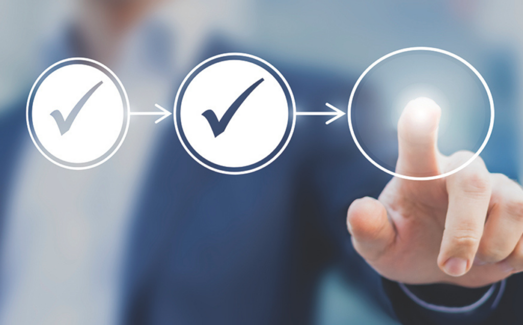 A person in a business suit points to a glowing circular icon on a transparent interface showing three connected circles, the first two marked complete and the third illuminated as the next step in a workflow.
