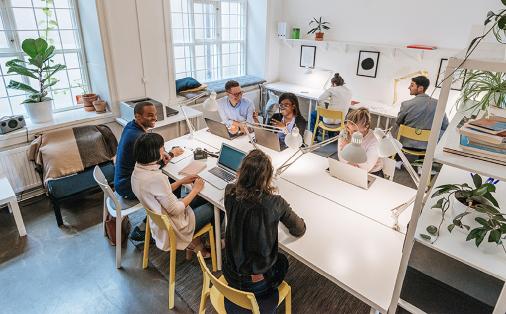 A modern office with people working together at large white desks.